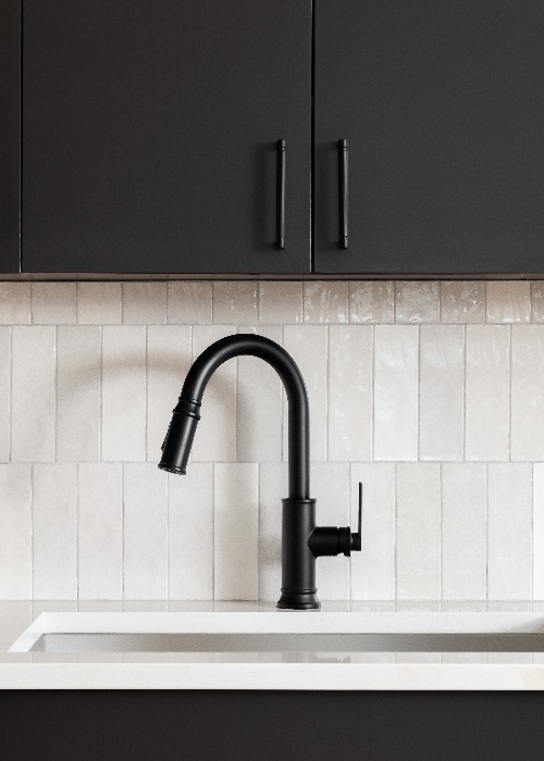 Black kitchen faucet and cabinets over a white tiled backsplash