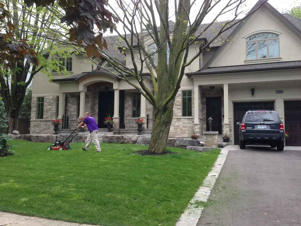 Worker mowing the front lawn of a house