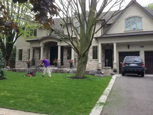 Worker mowing the front lawn of a house